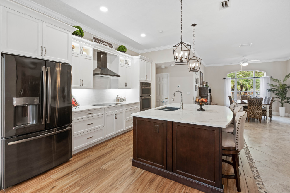 Inspiration for a huge transitional single-wall porcelain tile and multicolored floor eat-in kitchen remodel with a double-bowl sink, shaker cabinets, white cabinets, quartz countertops, white backsplash, porcelain backsplash, stainless steel appliances, white countertops and an island