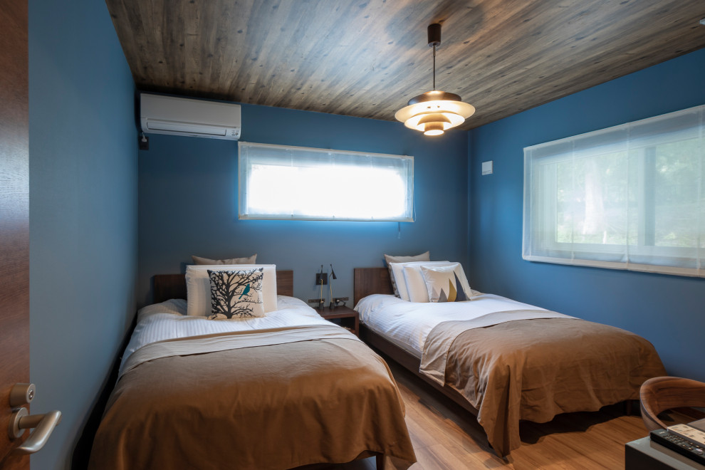 Idee per una piccola camera matrimoniale moderna con pareti blu, pavimento in compensato e pavimento marrone