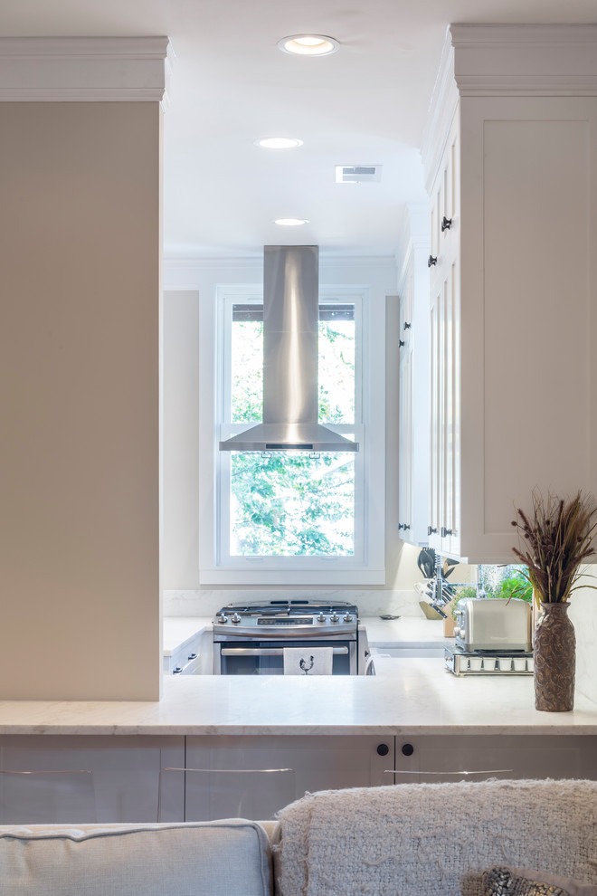 Inspiration for a mid-sized transitional galley medium tone wood floor and brown floor eat-in kitchen remodel in Chicago with a farmhouse sink, shaker cabinets, white cabinets, marble countertops, white backsplash, stone slab backsplash, stainless steel appliances and a peninsula