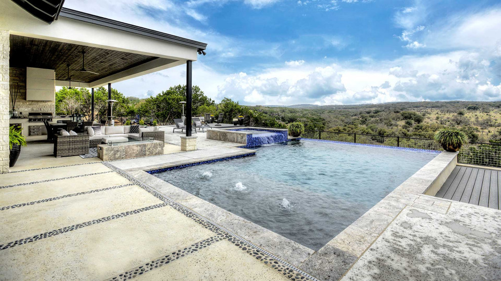 Photo of a large backyard rectangular infinity pool in Austin with with privacy feature and concrete slab.