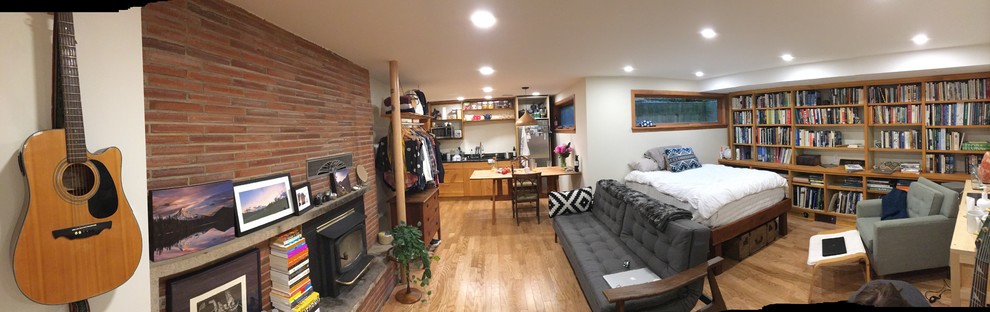 Mid-sized mountain style underground laminate floor and brown floor basement photo in Seattle with green walls and a wood stove