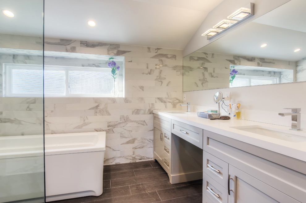 Photo of a large transitional master bathroom in Los Angeles with shaker cabinets, grey cabinets, a freestanding tub, a corner shower, multi-coloured tile, porcelain tile, white walls, porcelain floors, an undermount sink, engineered quartz benchtops, brown floor and a hinged shower door.