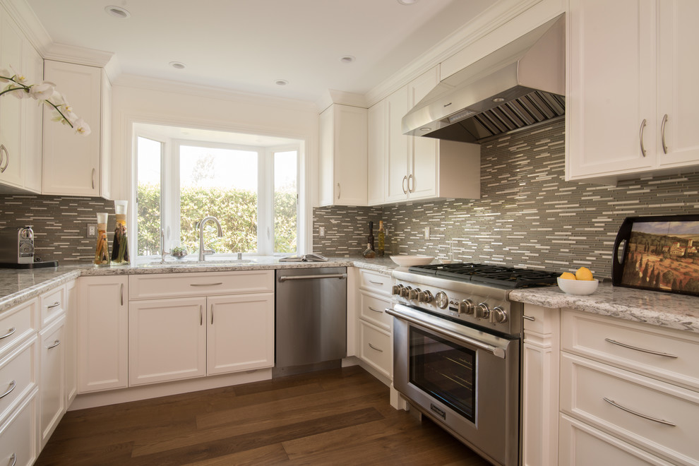 Eat-in kitchen - mid-sized transitional u-shaped dark wood floor eat-in kitchen idea in Los Angeles with an undermount sink, raised-panel cabinets, white cabinets, granite countertops, gray backsplash, matchstick tile backsplash and stainless steel appliances
