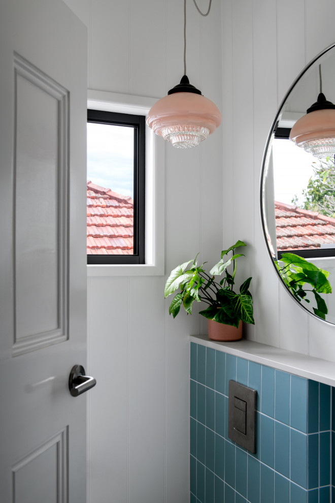 Photo of a small eclectic bathroom in Brisbane with light wood cabinets, a one-piece toilet, blue tile, porcelain tile, white walls, porcelain floors, a wall-mount sink, granite benchtops, grey floor, pink benchtops and a single vanity.
