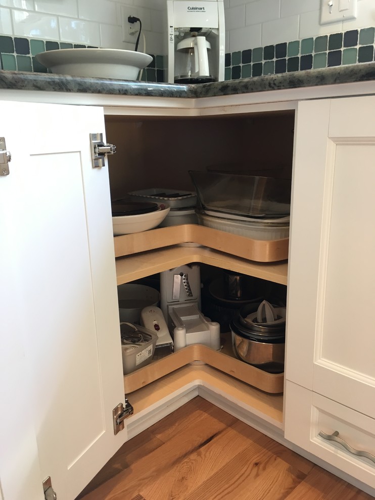 Example of a mid-sized transitional l-shaped light wood floor enclosed kitchen design with an undermount sink, flat-panel cabinets, white cabinets, granite countertops, white backsplash, subway tile backsplash, stainless steel appliances and no island
