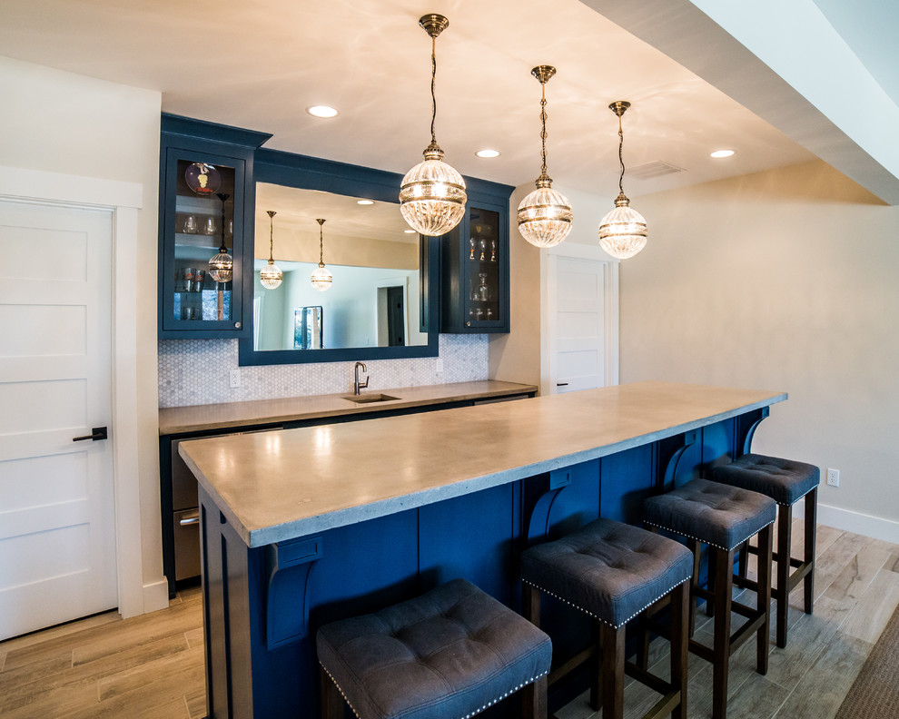 Inspiration for a mid-sized transitional single-wall seated home bar in Other with an undermount sink, shaker cabinets, blue cabinets, solid surface benchtops, white splashback, mosaic tile splashback and vinyl floors.