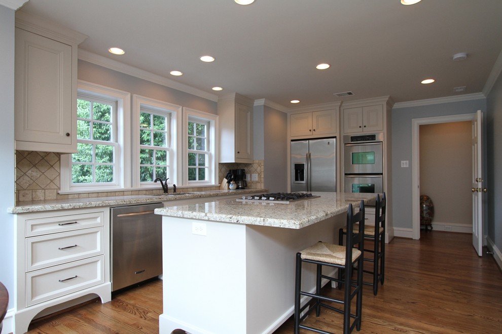Inspiration for a mid-sized traditional l-shaped eat-in kitchen in Houston with an undermount sink, beaded inset cabinets, white cabinets, granite benchtops, stainless steel appliances, medium hardwood floors and with island.