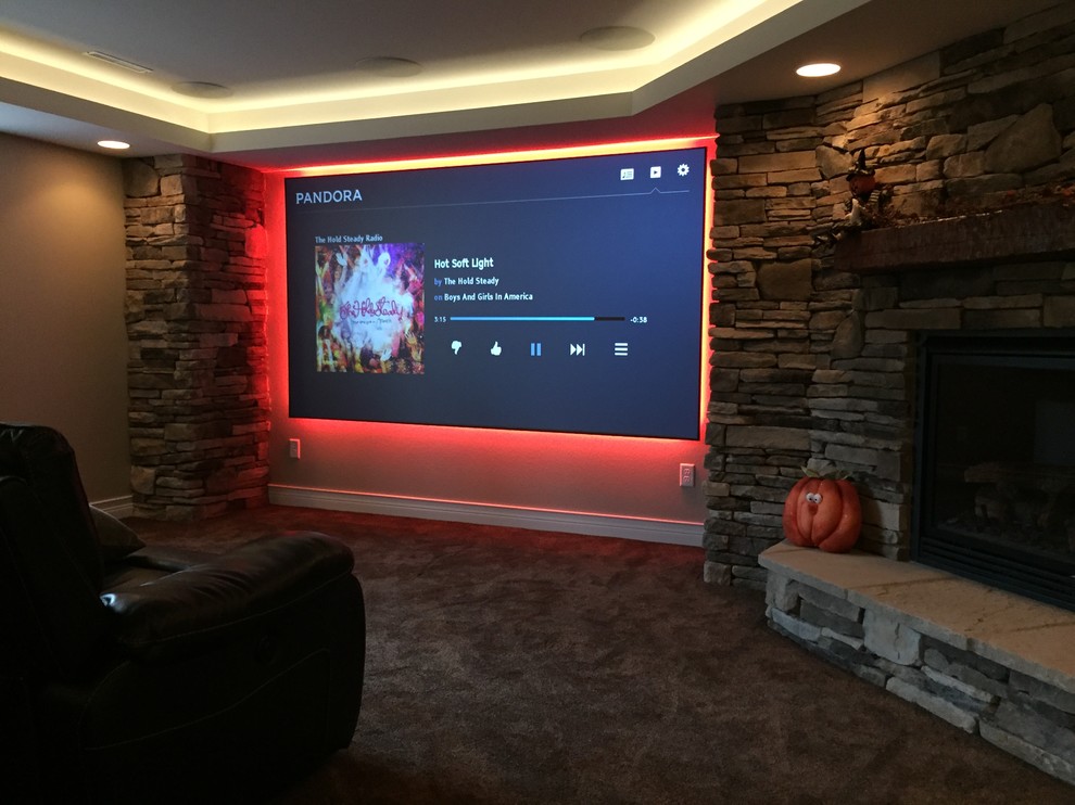 This is an example of a mid-sized contemporary enclosed home theatre in Other with a projector screen, beige walls and carpet.
