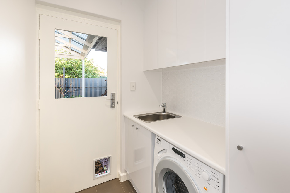 This is an example of a small contemporary single-wall dedicated laundry room in Other with a single-bowl sink, white cabinets, laminate benchtops, white walls, ceramic floors and a side-by-side washer and dryer.