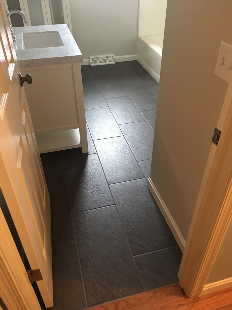 Inspiration for a mid-sized timeless 3/4 porcelain tile and gray tile porcelain tile and black floor alcove bathtub remodel with shaker cabinets, white cabinets, white walls, an undermount sink, marble countertops and a two-piece toilet