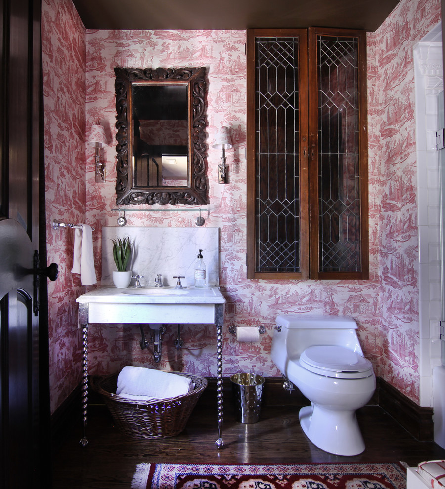 Mid-sized eclectic master bathroom in New York with a pedestal sink, glass-front cabinets, medium wood cabinets, marble benchtops, a corner tub, an alcove shower, a one-piece toilet, white tile, ceramic tile, multi-coloured walls and dark hardwood floors.