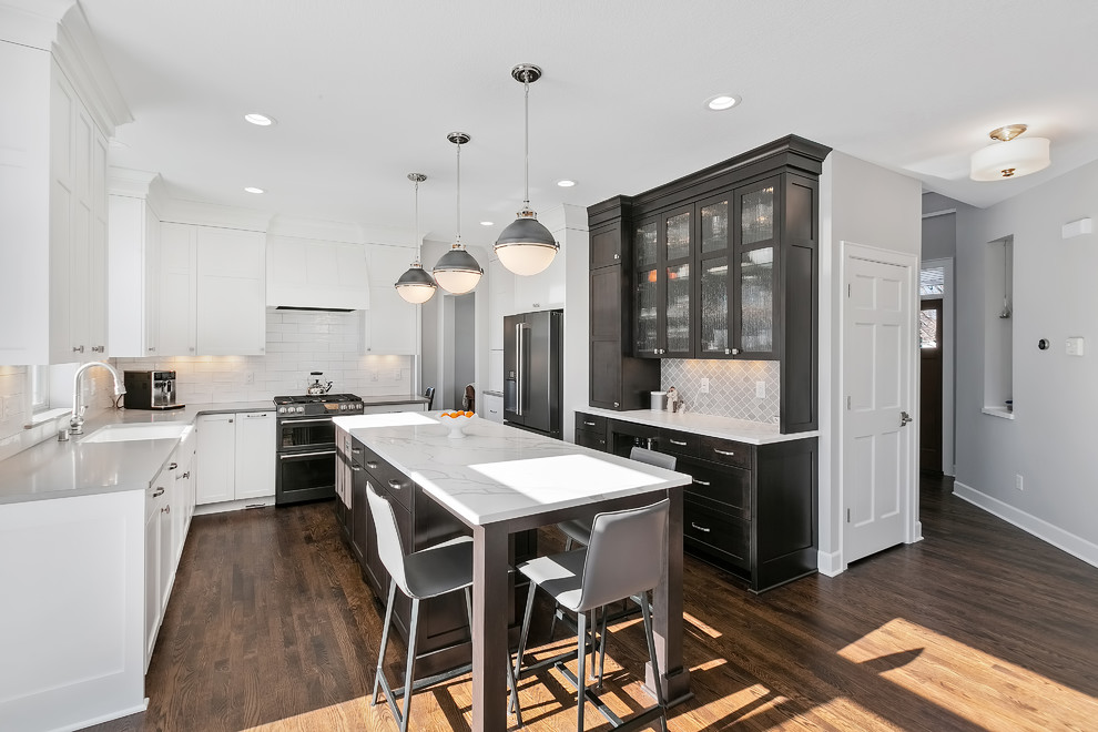 Inspiration for a mid-sized transitional u-shaped eat-in kitchen in Minneapolis with a farmhouse sink, white splashback, with island, brown floor, white benchtop, recessed-panel cabinets, white cabinets, quartzite benchtops, subway tile splashback, stainless steel appliances and dark hardwood floors.