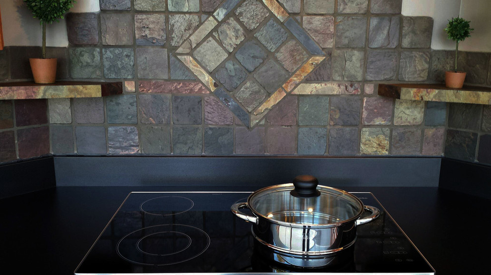 Mid-sized mountain style l-shaped slate floor home design photo with flat-panel cabinets, medium tone wood cabinets, laminate countertops, multicolored backsplash, stone tile backsplash, black appliances and no island