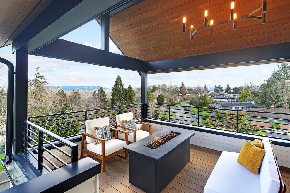 Photo of a mid-sized scandinavian deck in Seattle with a fire feature and a roof extension.