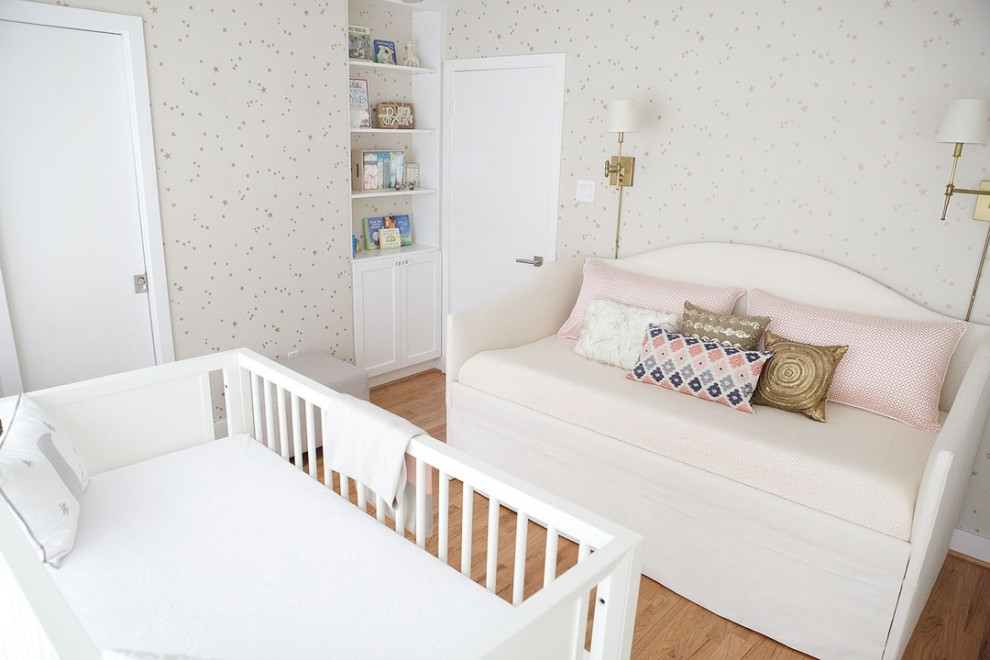 Modelo de habitación de bebé neutra actual de tamaño medio con paredes blancas y suelo de madera en tonos medios