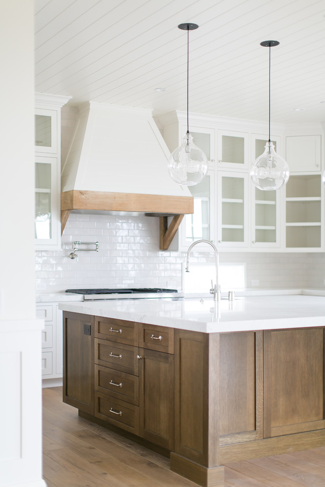 Inspiration for a large transitional u-shaped light wood floor and brown floor open concept kitchen remodel in Orange County with a farmhouse sink, shaker cabinets, white cabinets, marble countertops, white backsplash, subway tile backsplash, stainless steel appliances and an island