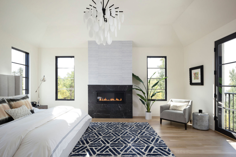 Photo of a large contemporary master bedroom in Denver with white walls, light hardwood floors, a ribbon fireplace, a tile fireplace surround and beige floor.