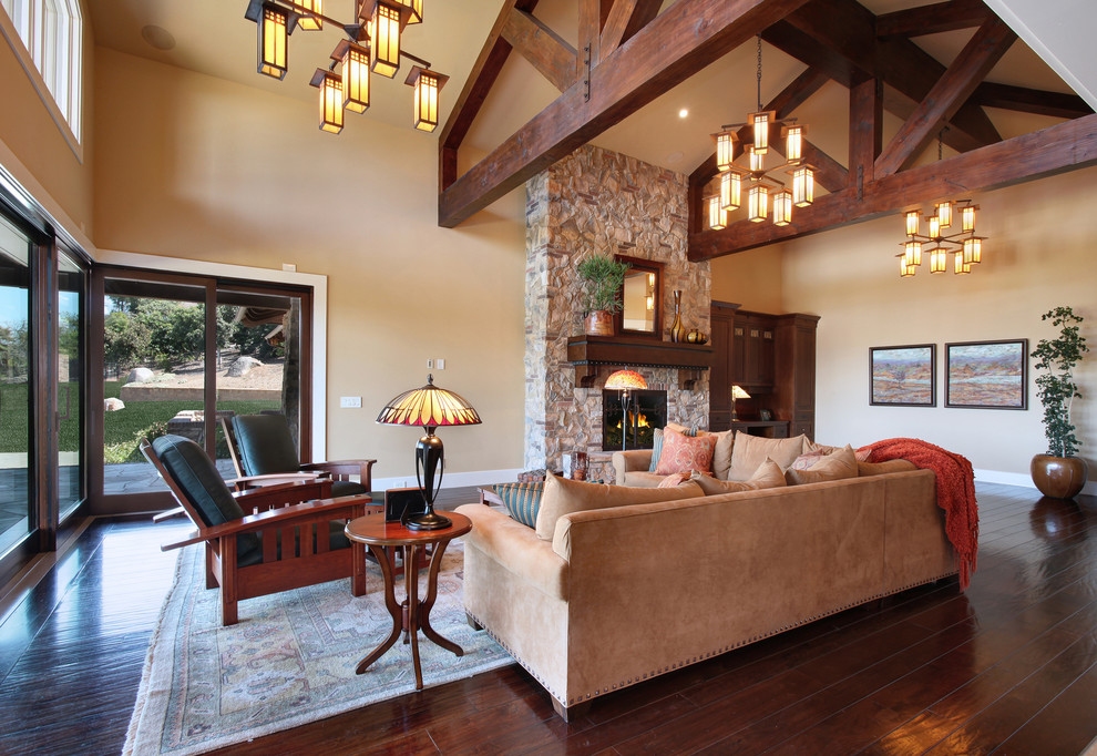 Inspiration for a large arts and crafts formal open concept living room in San Diego with beige walls, dark hardwood floors, a hanging fireplace, a stone fireplace surround, no tv and brown floor.
