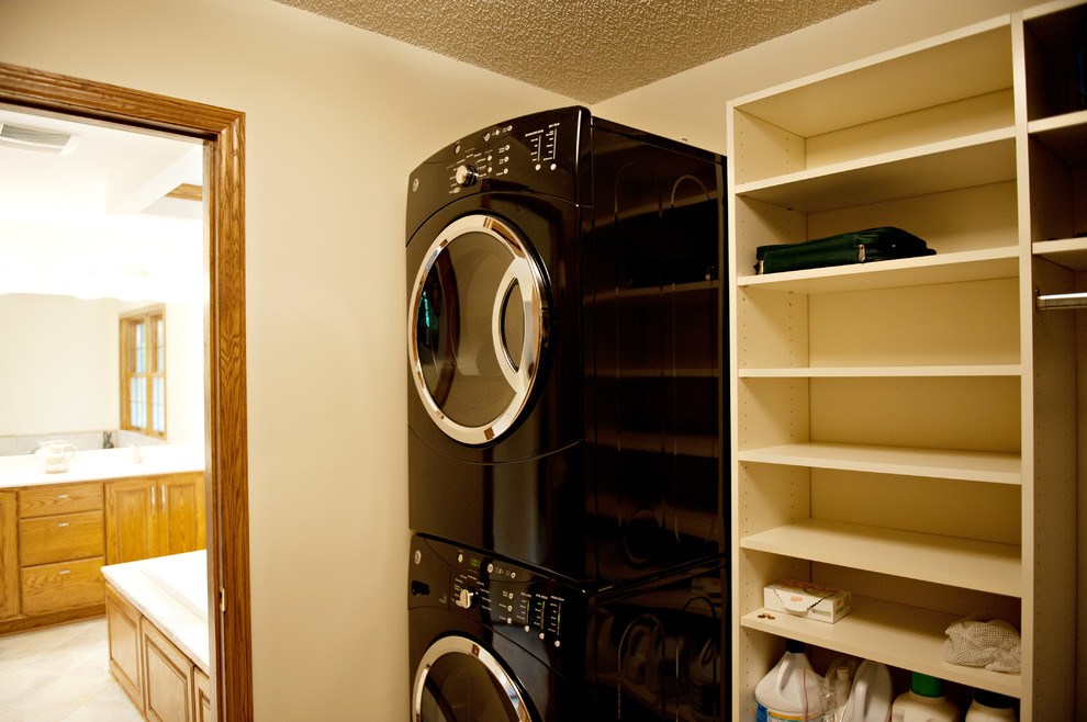 Photo of a mid-sized laundry cupboard in Minneapolis with white cabinets and a stacked washer and dryer.