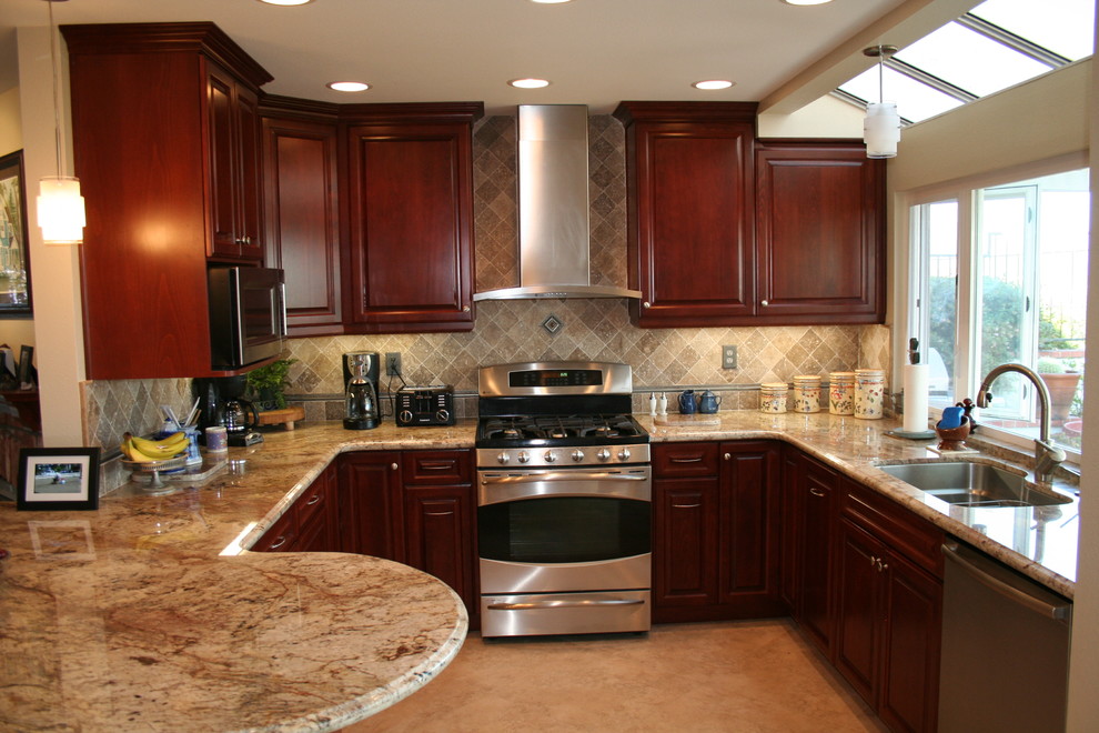 Example of a mid-sized transitional u-shaped limestone floor eat-in kitchen design in Orange County with raised-panel cabinets, dark wood cabinets, stainless steel appliances, a single-bowl sink, granite countertops, beige backsplash, limestone backsplash and a peninsula