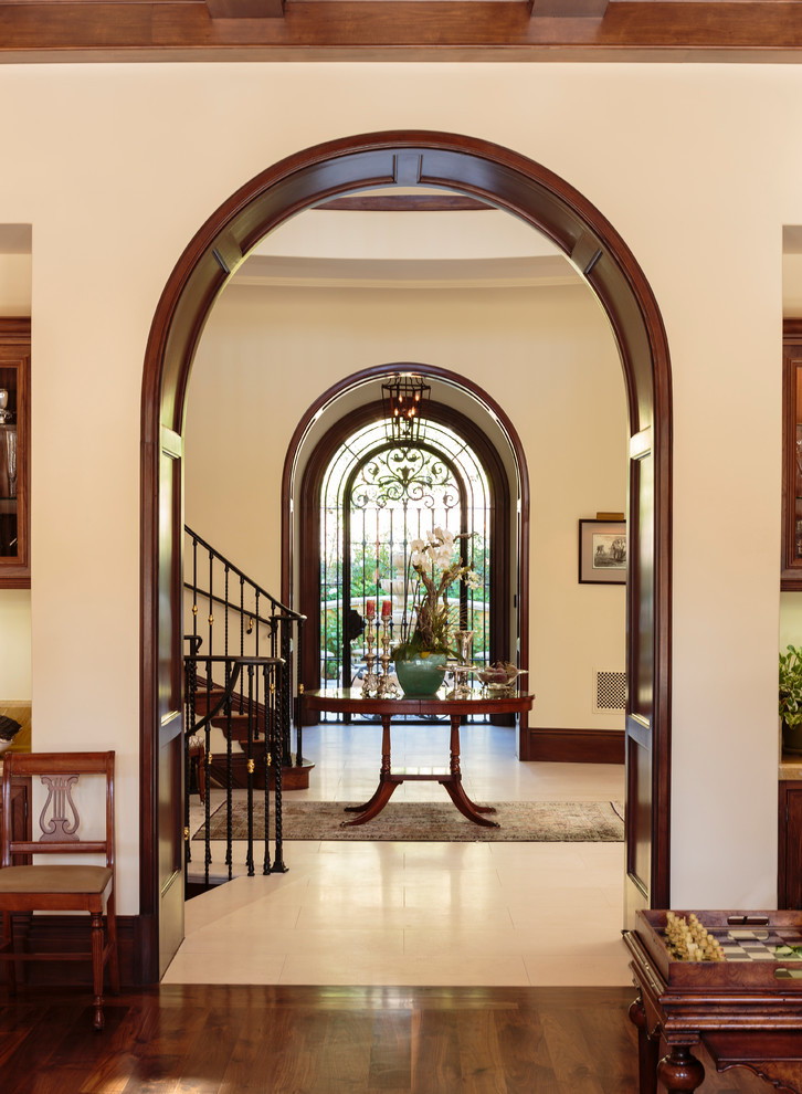 This is an example of an expansive mediterranean foyer in Los Angeles with beige walls, dark hardwood floors, a single front door and a metal front door.