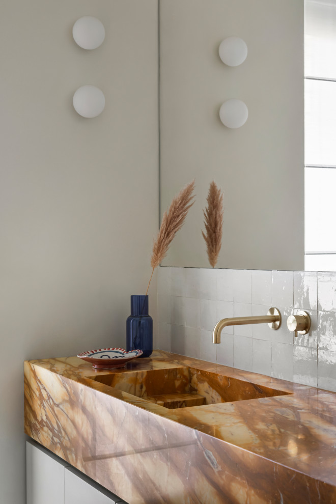 Bild på ett mellanstort funkis gul gult badrum med dusch, med släta luckor, vita skåp, en kantlös dusch, en toalettstol med separat cisternkåpa, vit kakel, perrakottakakel, vita väggar, marmorgolv, ett avlångt handfat, marmorbänkskiva, beiget golv och med dusch som är öppen