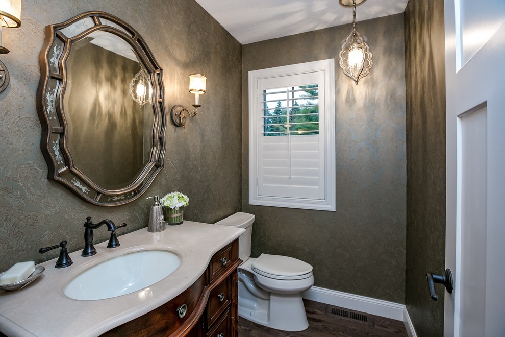 This is an example of a mid-sized transitional 3/4 bathroom in Minneapolis with beaded inset cabinets, dark wood cabinets, a one-piece toilet, multi-coloured walls, dark hardwood floors, an undermount sink and solid surface benchtops.
