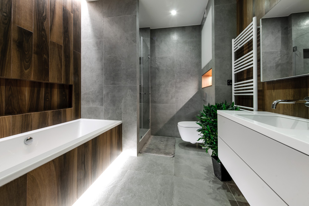 This is an example of a contemporary master bathroom in Moscow with flat-panel cabinets, white cabinets, an alcove tub, an alcove shower, a wall-mount toilet, brown tile, gray tile, an undermount sink, grey floor, a hinged shower door, white benchtops, a single vanity and a floating vanity.