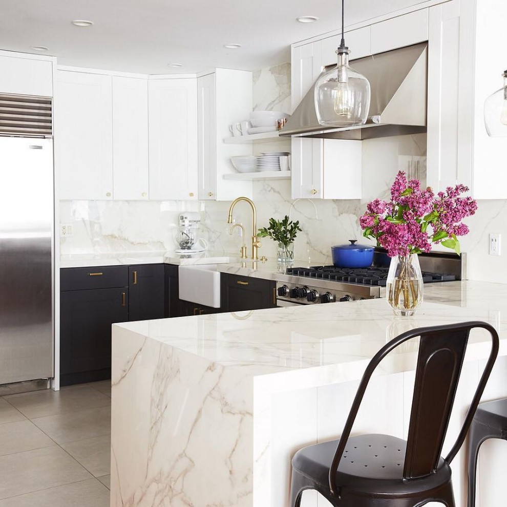 Contemporary u-shaped kitchen in Los Angeles with a farmhouse sink, raised-panel cabinets, black cabinets, white splashback, stainless steel appliances, a peninsula, grey floor and white benchtop.