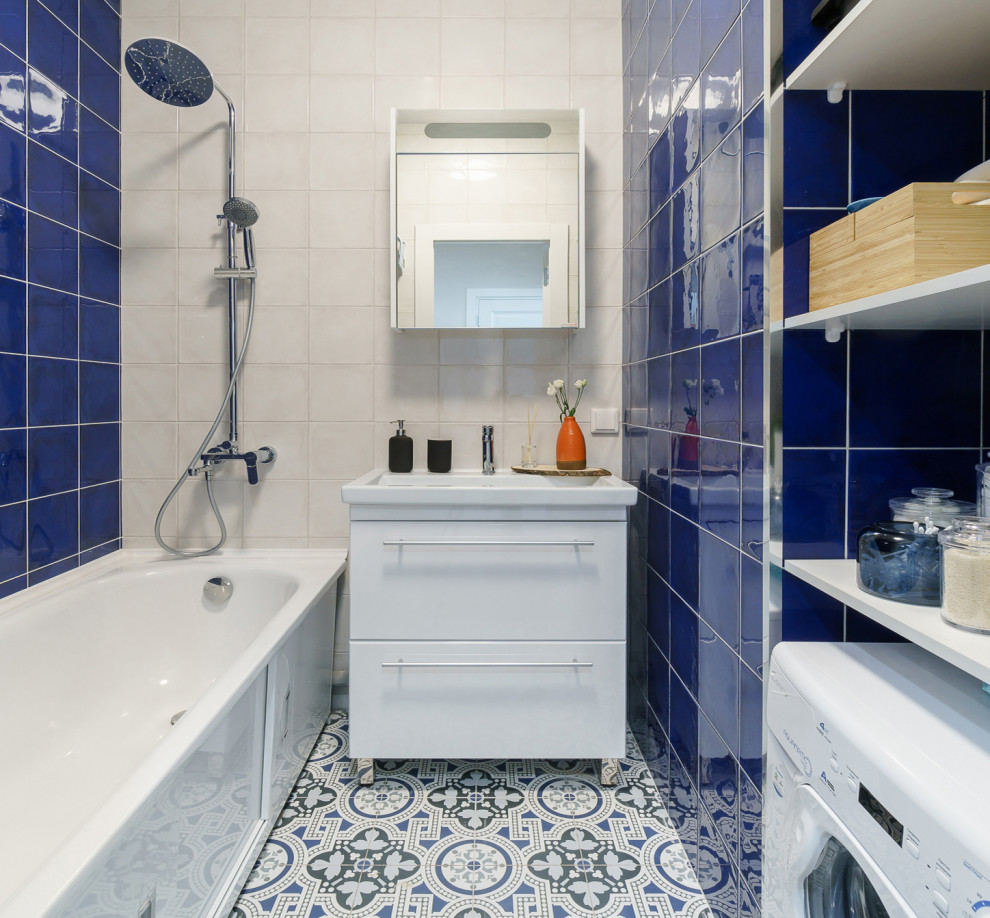 This is an example of a small contemporary master bathroom in Saint Petersburg with flat-panel cabinets, white cabinets, a freestanding tub, blue tile, ceramic tile, white walls, ceramic floors, a drop-in sink, multi-coloured floor, a laundry, a single vanity and a freestanding vanity.