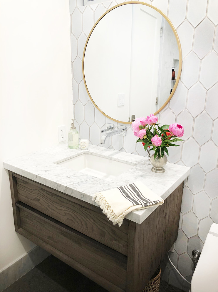 Small contemporary kids bathroom in Santa Barbara with dark wood cabinets, a drop-in tub, a shower/bathtub combo, a wall-mount toilet, white tile, terra-cotta tile, white walls, porcelain floors, an undermount sink, marble benchtops, grey floor, a hinged shower door and white benchtops.