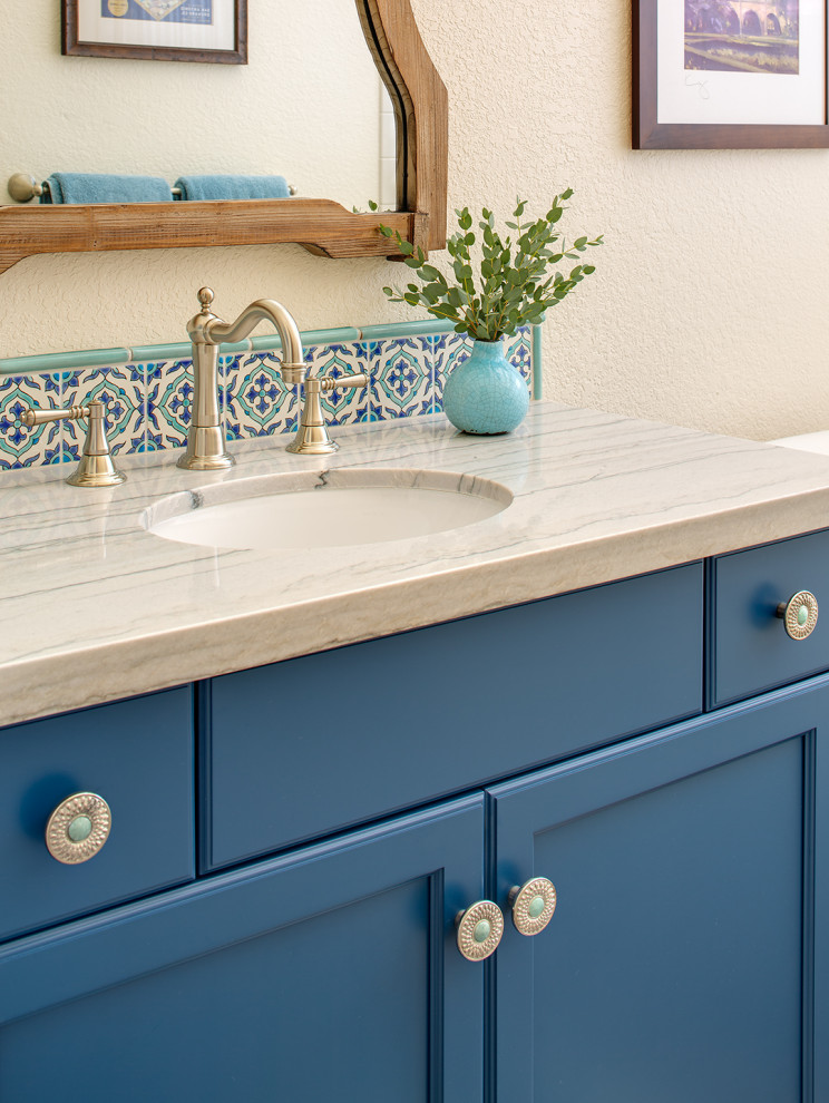 Imagen de aseo a medida mediterráneo pequeño con armarios con paneles lisos, puertas de armario azules, baldosas y/o azulejos beige, encimera de cuarcita y encimeras beige