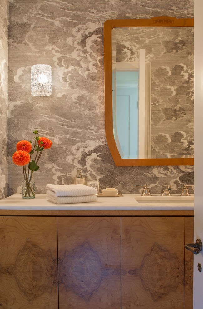 This is an example of a mid-sized transitional powder room in Los Angeles with flat-panel cabinets, medium wood cabinets, grey walls, an undermount sink and marble benchtops.