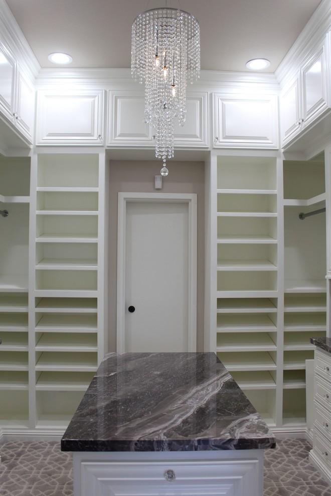 Photo of a mid-sized traditional walk-in wardrobe in Other with raised-panel cabinets, white cabinets and carpet.