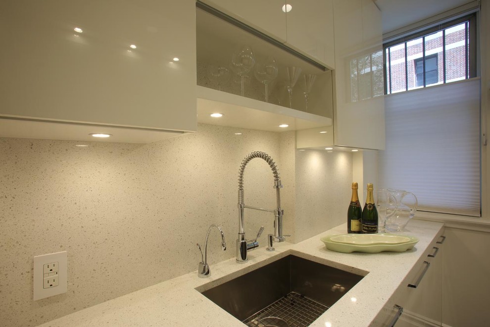 Photo of a mid-sized modern galley separate kitchen in New York with an undermount sink, flat-panel cabinets, white cabinets, stainless steel appliances, medium hardwood floors, no island, terrazzo benchtops, white splashback and stone tile splashback.