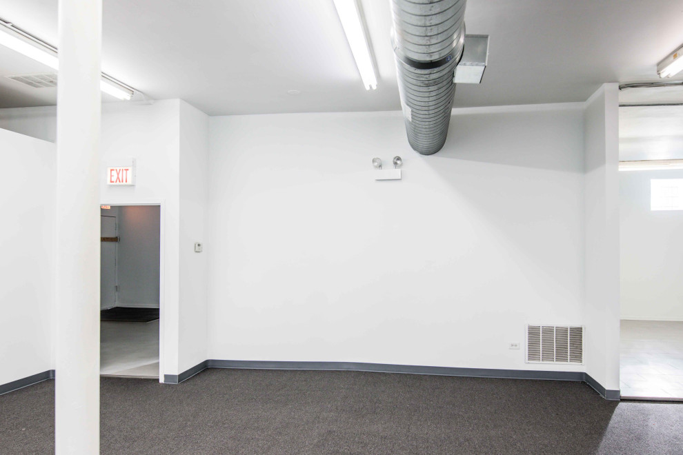 Aménagement d'un couloir rétro avec un mur blanc, moquette et un sol gris.