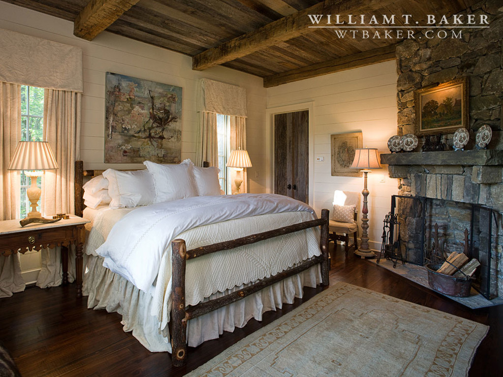 This is an example of a mid-sized country master bedroom in Atlanta with white walls, dark hardwood floors, a corner fireplace and a stone fireplace surround.