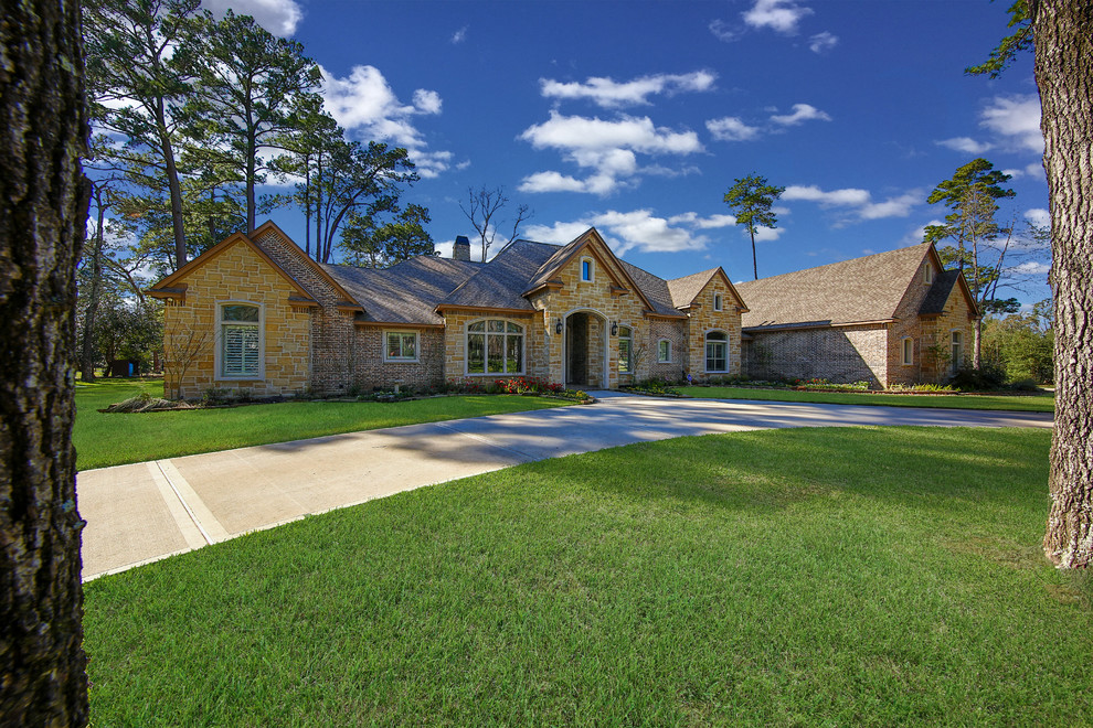 Photo of a mid-sized country two-storey beige exterior in Houston with stone veneer and a gable roof.