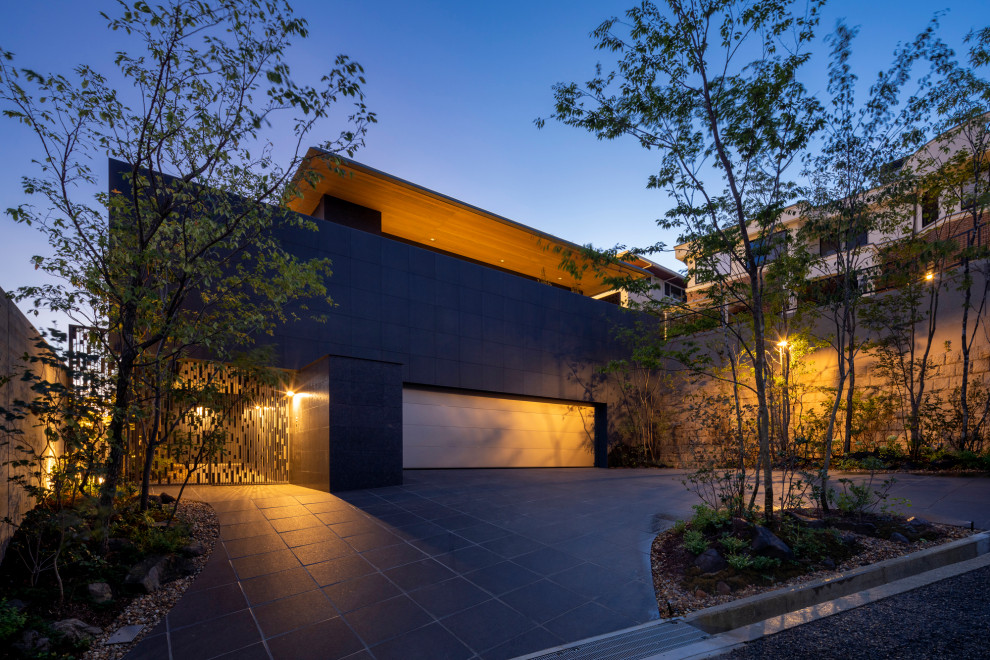 This is an example of an expansive modern two-storey black house exterior in Kobe with stone veneer, a hip roof, a metal roof and a grey roof.