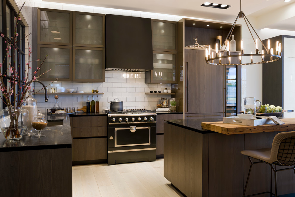 Inspiration for a contemporary l-shaped kitchen in DC Metro with flat-panel cabinets, dark wood cabinets, white splashback, light hardwood floors, with island, an undermount sink, subway tile splashback and panelled appliances.