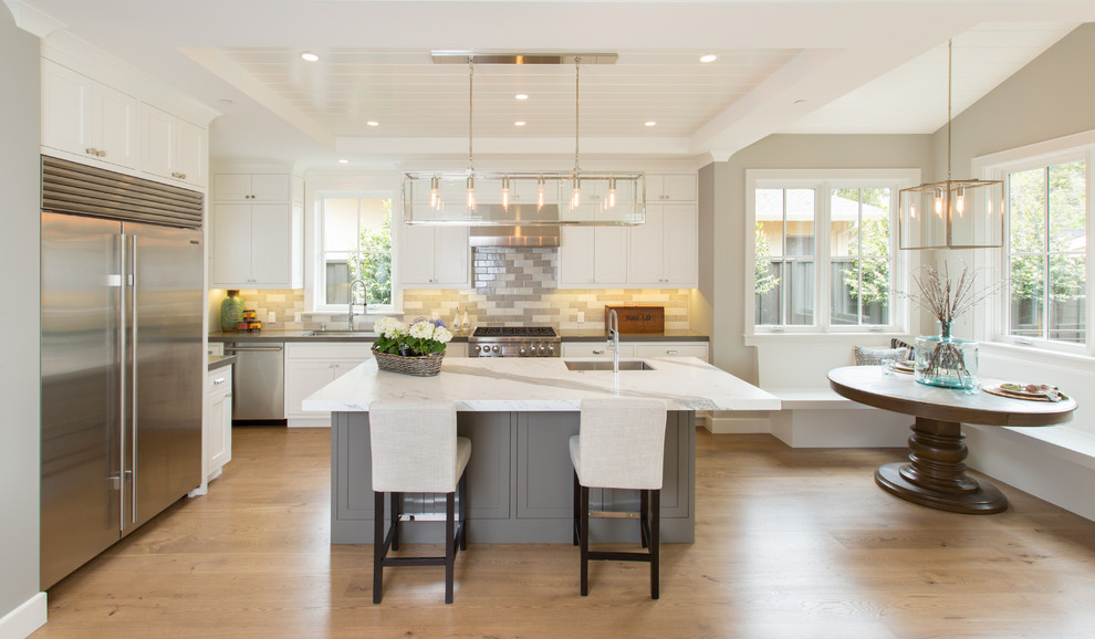 Large transitional l-shaped eat-in kitchen in San Francisco with an undermount sink, subway tile splashback, stainless steel appliances, medium hardwood floors, with island, shaker cabinets, grey cabinets, grey splashback and granite benchtops.