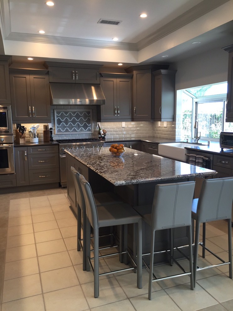 Kitchen pantry - large transitional u-shaped porcelain tile kitchen pantry idea in Los Angeles with a farmhouse sink, shaker cabinets, gray cabinets, granite countertops, beige backsplash, ceramic backsplash, stainless steel appliances and an island