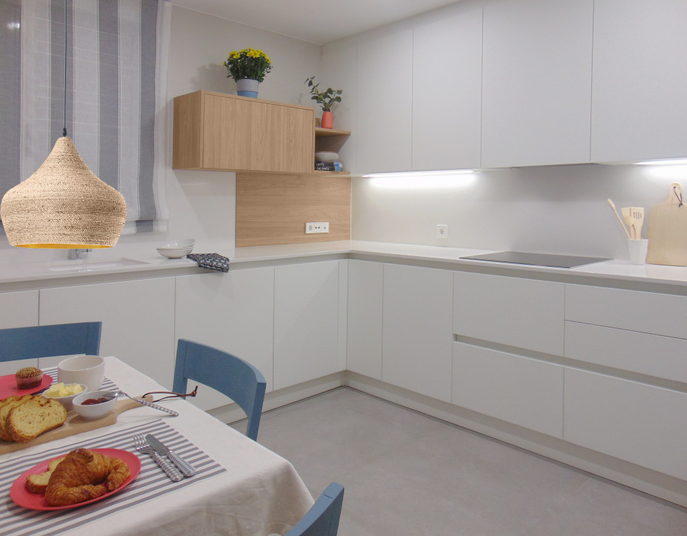 Photo of a mid-sized scandinavian u-shaped kitchen in Barcelona with an undermount sink, white cabinets, quartz benchtops, black appliances, porcelain floors, grey floor and white benchtop.