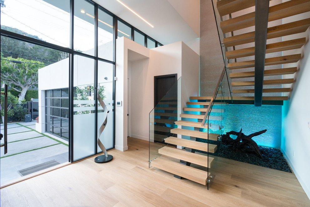 Contemporary wood u-shaped staircase in Los Angeles with open risers and glass railing.