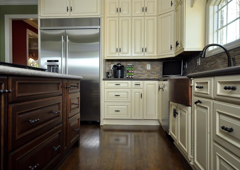 Mid-sized transitional l-shaped dark wood floor eat-in kitchen photo with raised-panel cabinets, white cabinets, multicolored backsplash, mosaic tile backsplash, stainless steel appliances, an island, a farmhouse sink and granite countertops