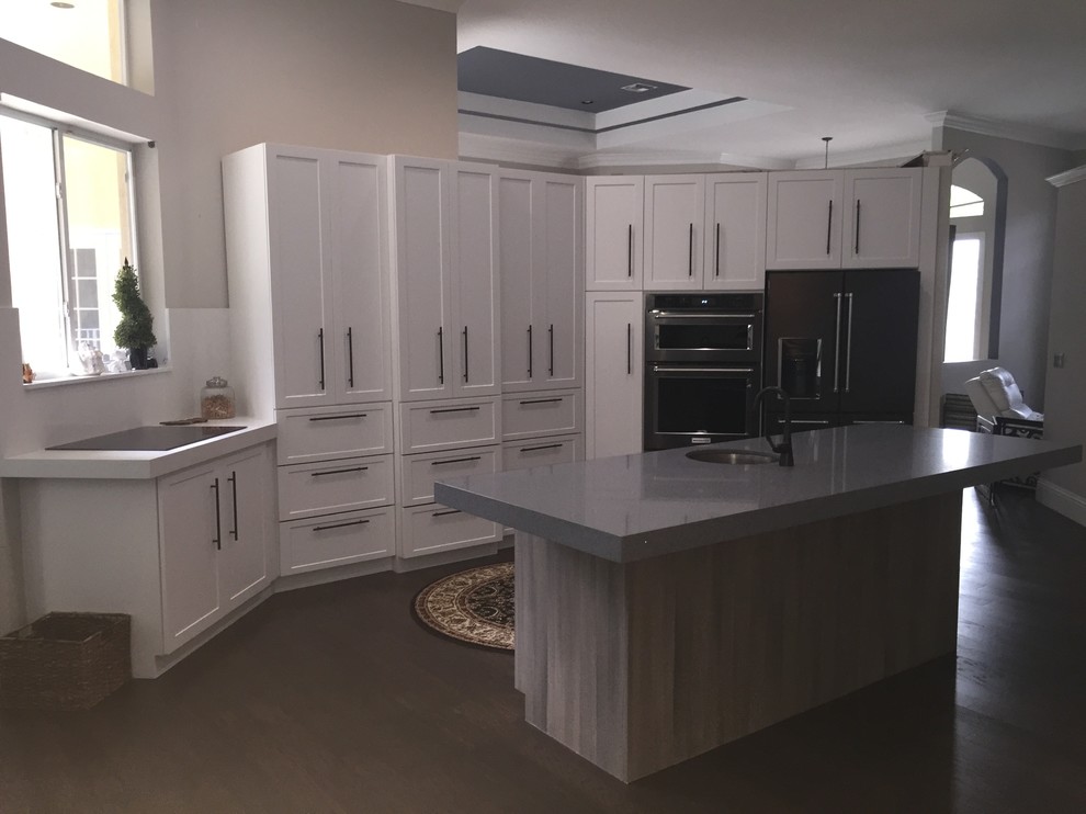 Inspiration for a mid-sized transitional single-wall eat-in kitchen in Miami with an undermount sink, shaker cabinets, quartz benchtops, white splashback, stone slab splashback, stainless steel appliances, medium hardwood floors and with island.