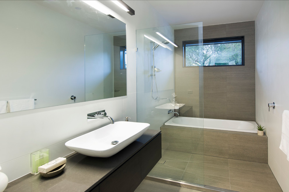 Inspiration for a contemporary bathroom in Melbourne with a vessel sink, flat-panel cabinets, dark wood cabinets, a drop-in tub, an open shower, gray tile, white walls and an open shower.