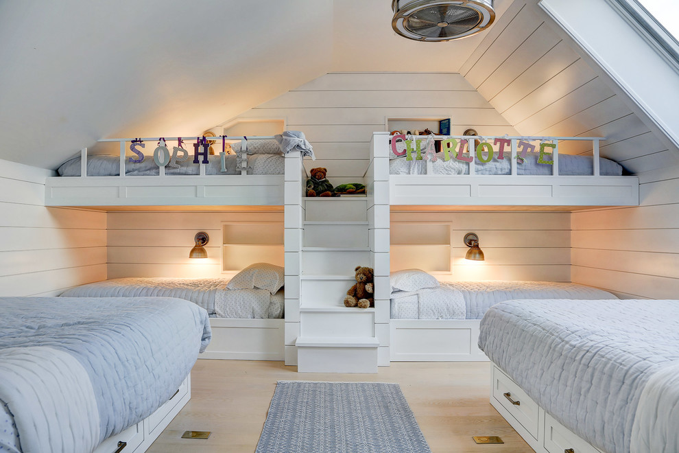 Design ideas for a mid-sized country gender-neutral kids' bedroom for kids 4-10 years old in New York with white walls, light hardwood floors and beige floor.