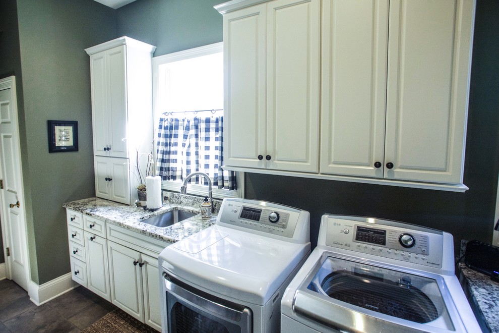This is an example of a mid-sized traditional galley utility room in Other with an undermount sink, raised-panel cabinets, white cabinets, granite benchtops, green walls and a side-by-side washer and dryer.