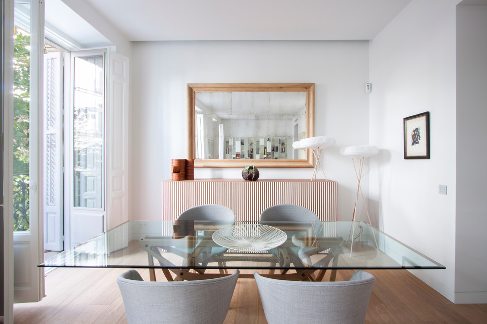 This is an example of a mid-sized scandinavian separate dining room in Madrid with light hardwood floors, white walls and no fireplace.